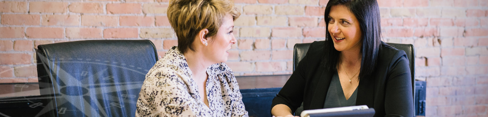 Two women seated in a conference room talking about their employment law needs